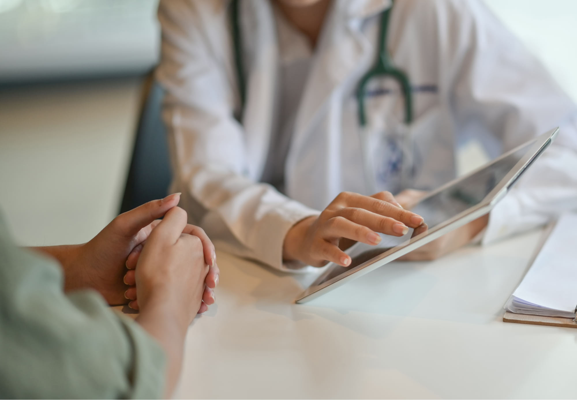 A doctor sits with a patient whilst reading through content on an iPad